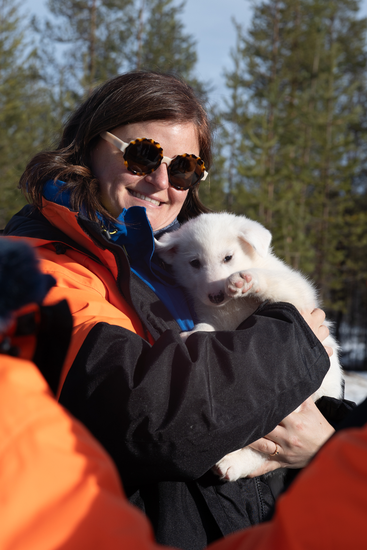 Guest cradling a fluffy white husky puppy at the farm