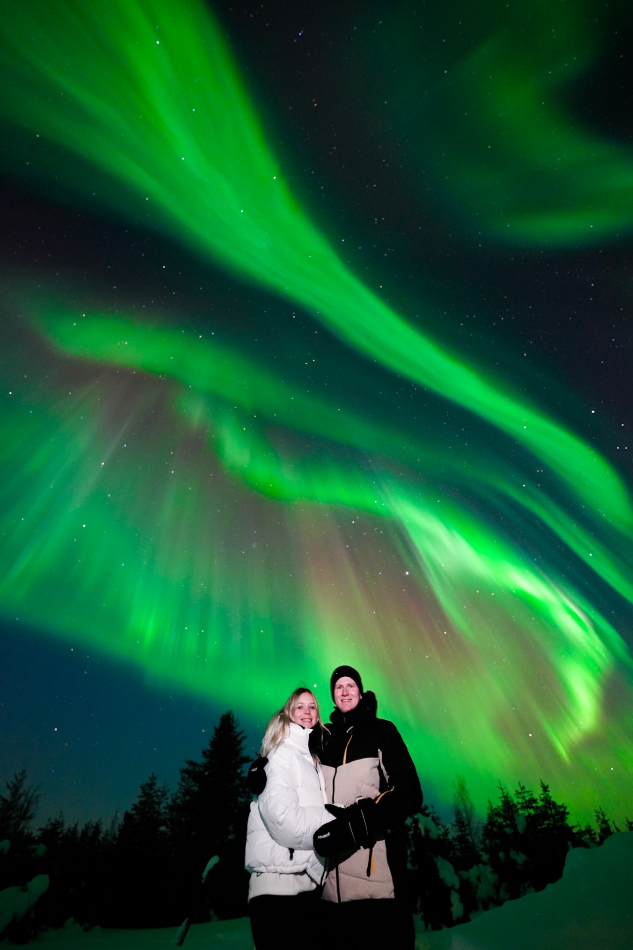 Couple under swirling green aurora