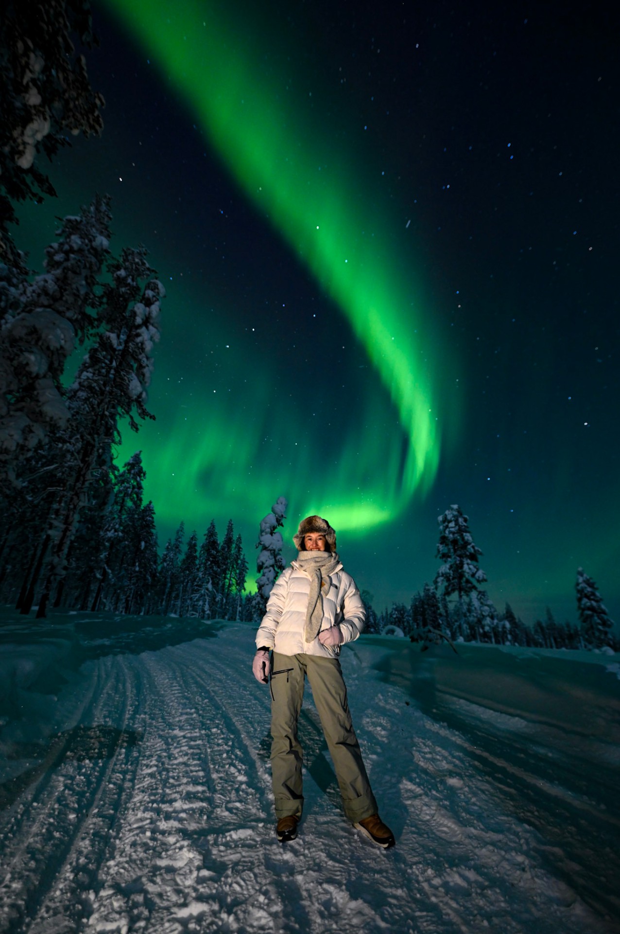 Guest on snowy trail under green aurora