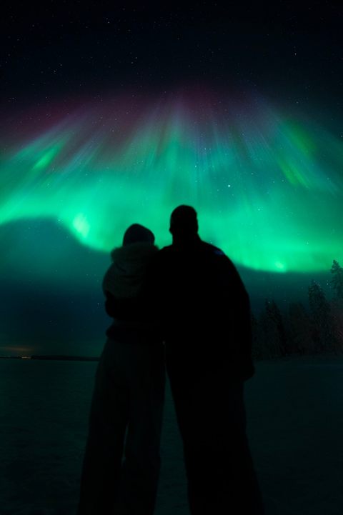 Paar umarmt sich unter grüner Aurora