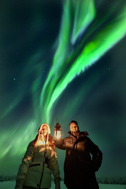 Una coppia con lanterne sotto un'aurora verde durante un tour Polar Lapland