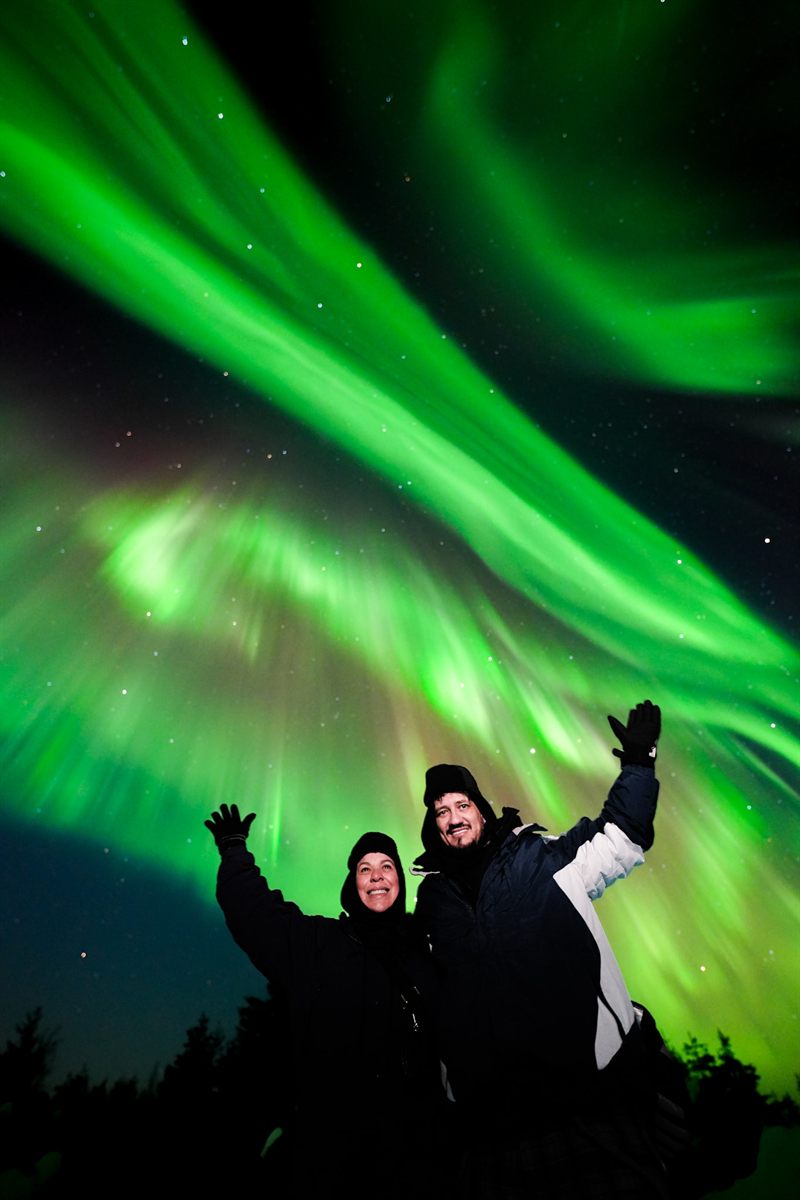 Family cheering under a bright aurora on a guaranteed Northern Lights tour