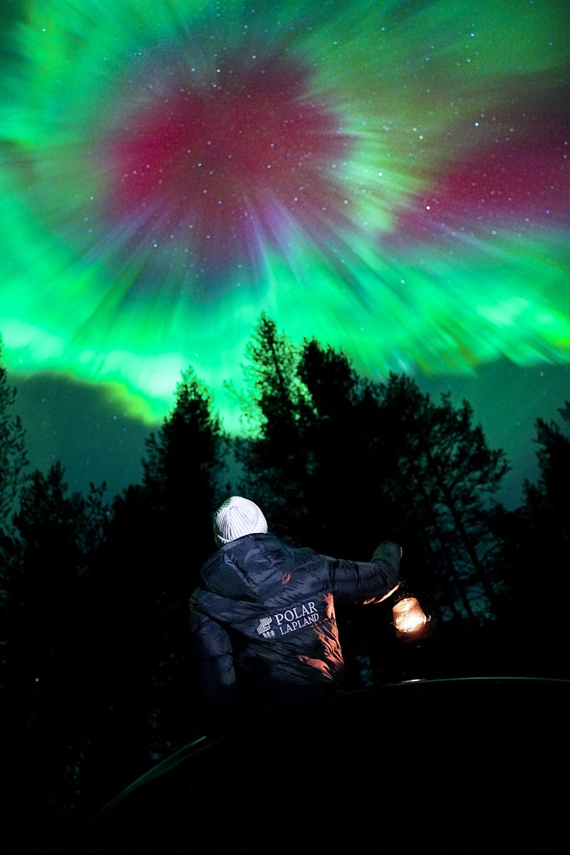 Guide photographing a guest beneath the northern lights