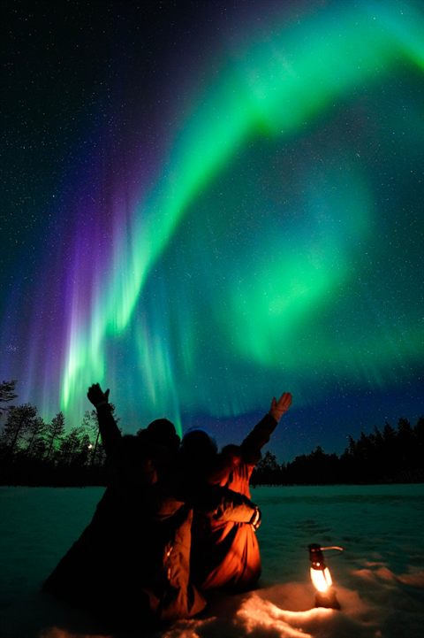 Paar jubelt unter den Nordlichtern auf einer Polar-Lapland-Nordlichtjagd