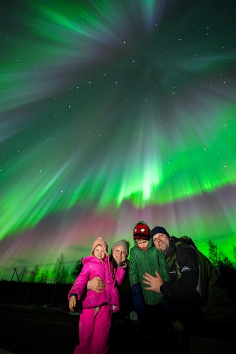 Familie unter einer grünen Aurora-Korona in Finnisch-Lappland