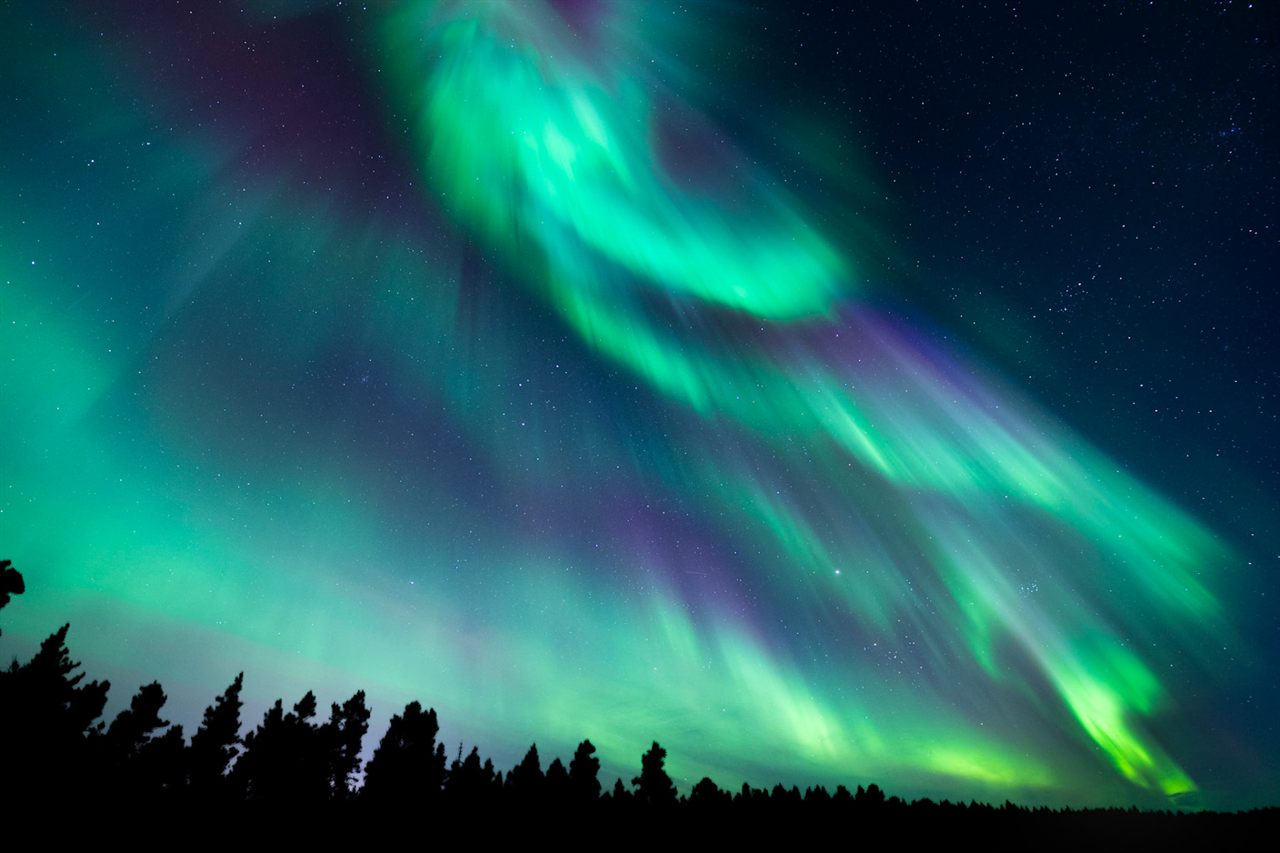 Aurora boreal sobre un lago helado y un bosque cerca de Rovaniemi, Laponia finlandesa