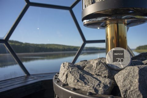 Saunasteine auf dem Harvia-Ofen im Glasiglu mit Blick auf einen ruhigen Lapplandsee