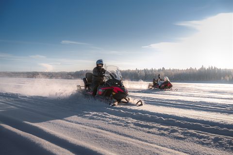 Schneemobile wirbeln Pulverschnee auf einer sonnigen Strecke bei Rovaniemi auf