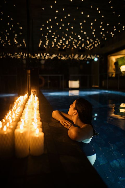 Guest resting at the edge of the candlelit vitality pool