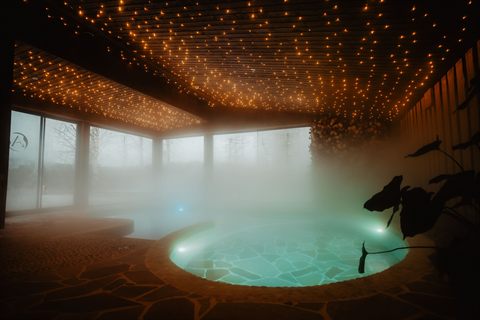 Steaming hot spring pool under a starry ceiling of lights in the spa