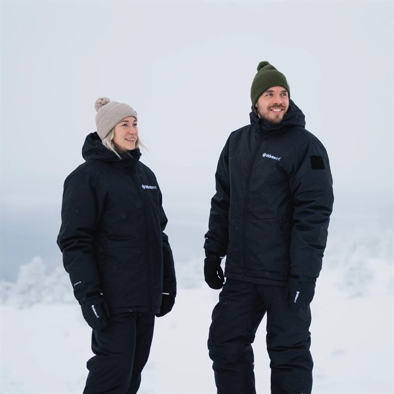 Two people in black rental winter jackets, trousers and mittens on a snowy fell